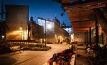 PURO - Lodź - Lidé na průchodu ve dvoře nájemního domu v ulici Piotrkowska v Lodži. Stěny budovy zdobené kusy zrcadel. Městská scéna ve večerních hodinách.